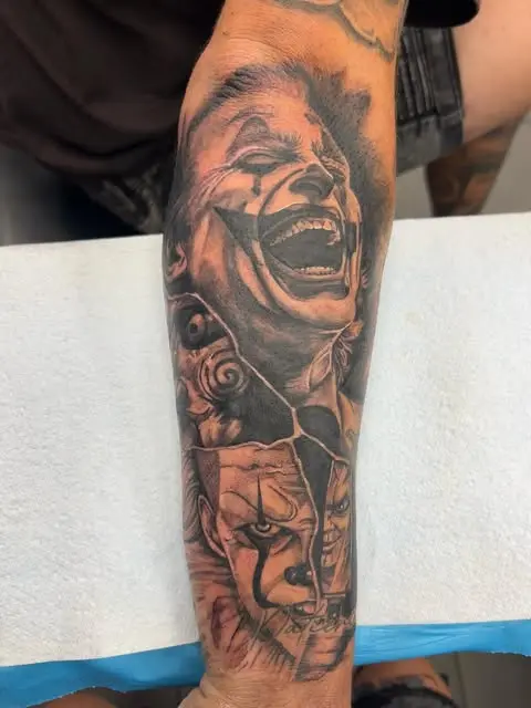 Black and grey forearm piece of a laughing Joker above a clown face